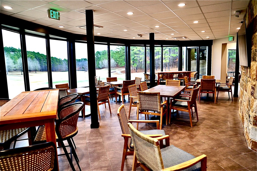 View of dining area from the back, brown interior with tables and chairs throughout. Window walls in the background.