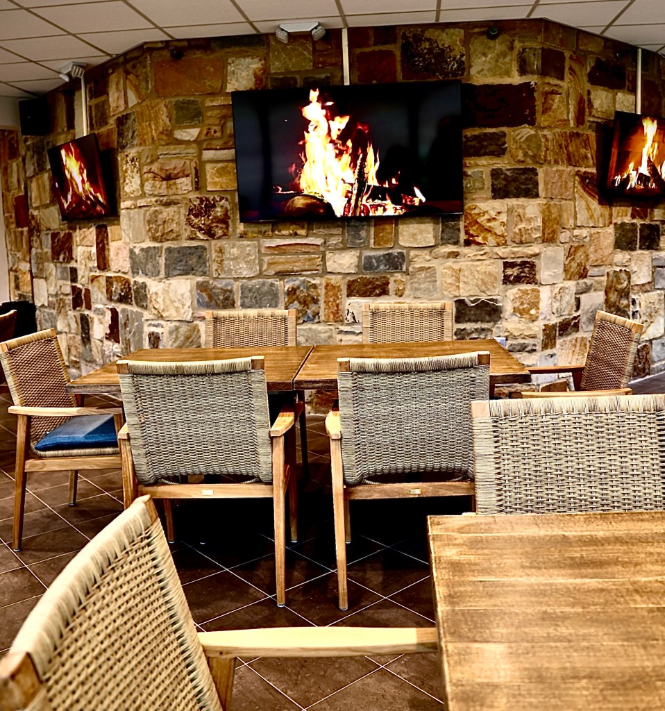 A fireplace near the ceiling in a corner of the dining area. A large table with chairs underneath.